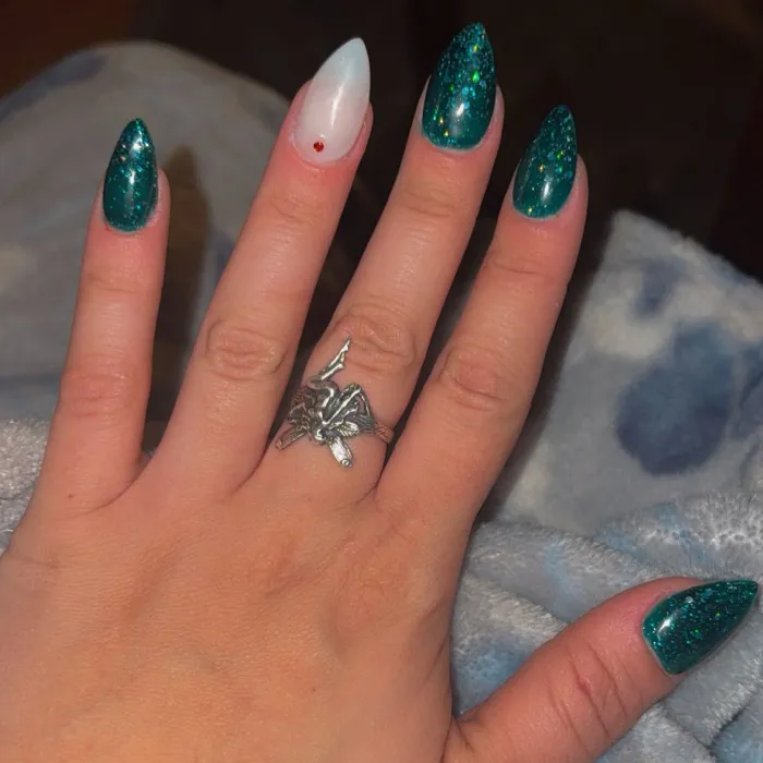 Long almond nails in emerald green glitter with one milky white accent nail