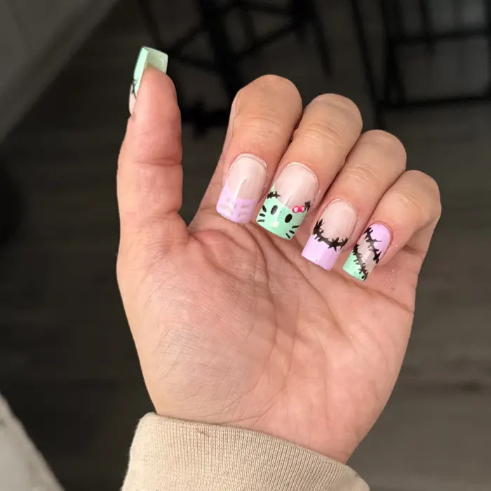 Long square nails with mint and lilac French tips, a hand-painted Frankenstein kitty and stitched scar accents