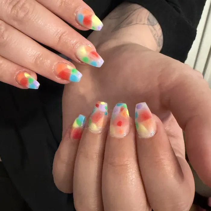Coffin nails over a clear base with soft rainbow aura dots in red, orange, yellow, green and blue